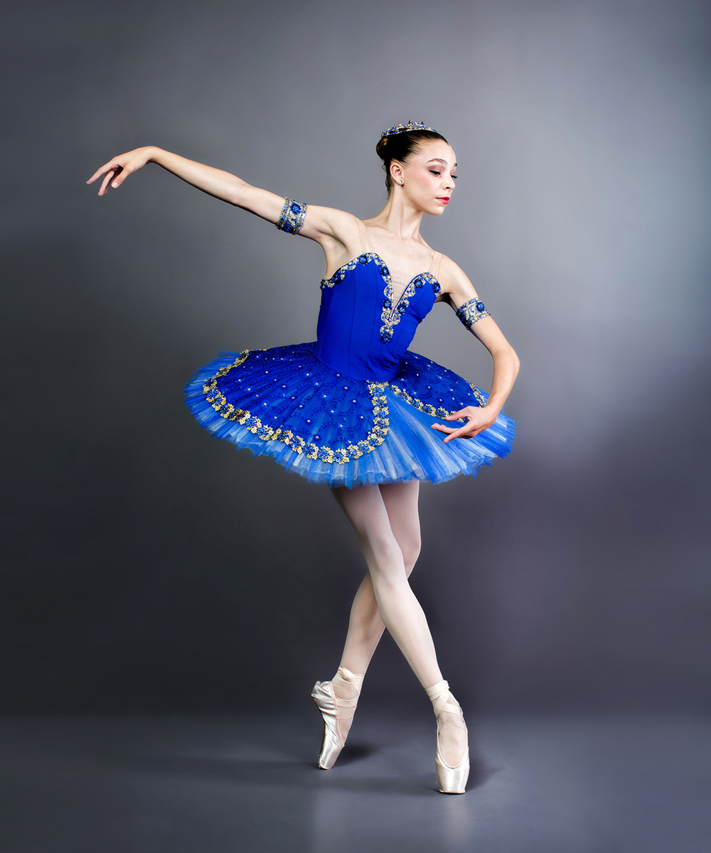 A ballerina in a blue classical tutu poised on pointe