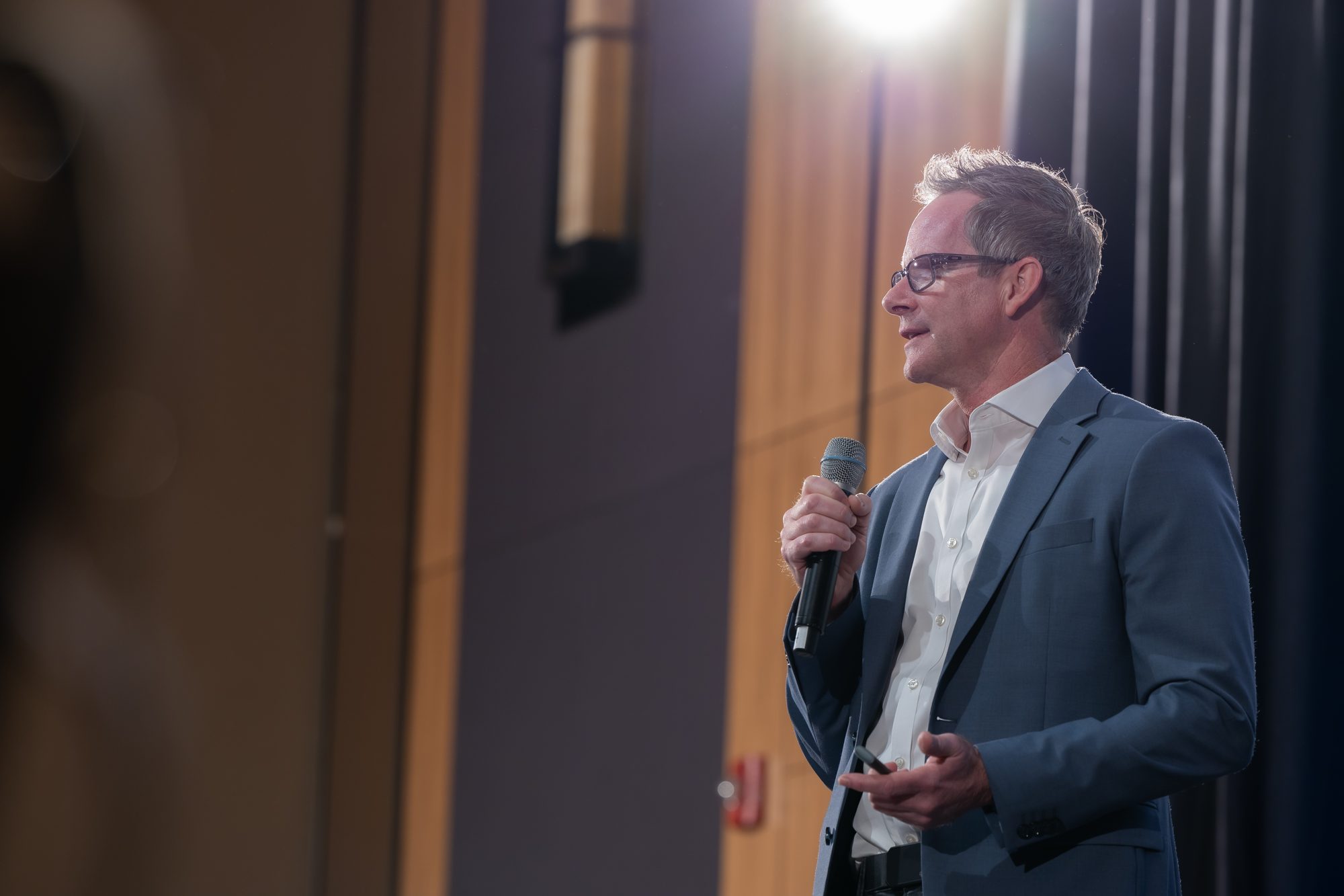 A presenter speaking with a microphone on stage at a conference