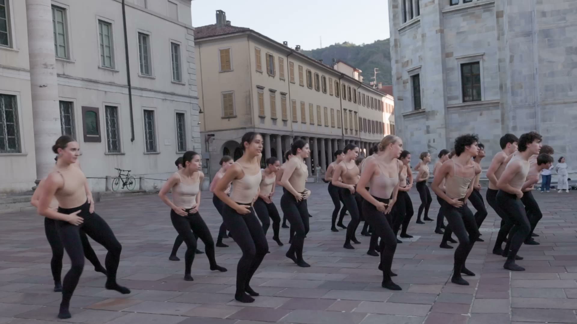 Dancers performing in formation in a historic European piazza